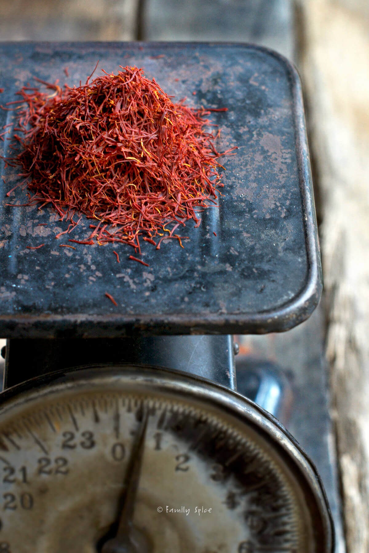 Closeup of a small mound of saffron threads on a black antique scale.