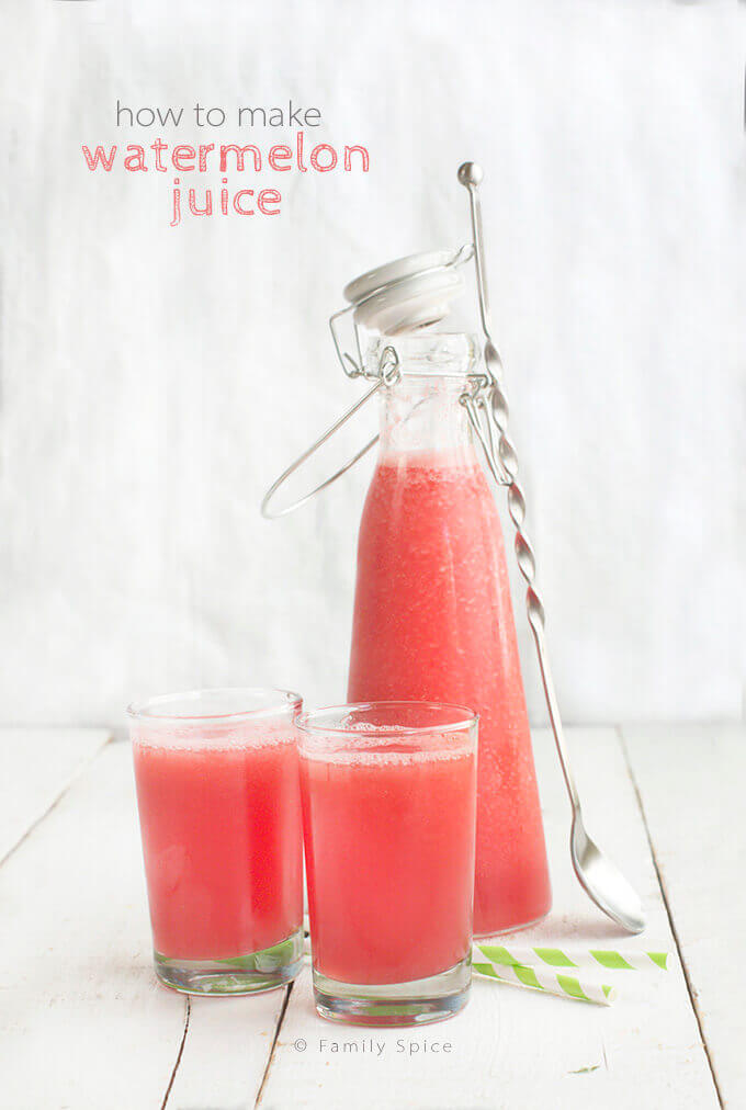 Two small glasses of watermelon juice with a small carafe behind it and a tall spoon next to it