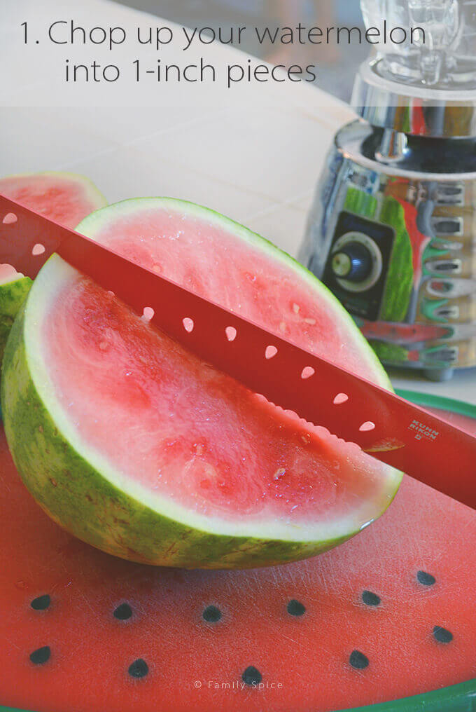 A small watermelon cut in half with a watermelon cutting knife in it