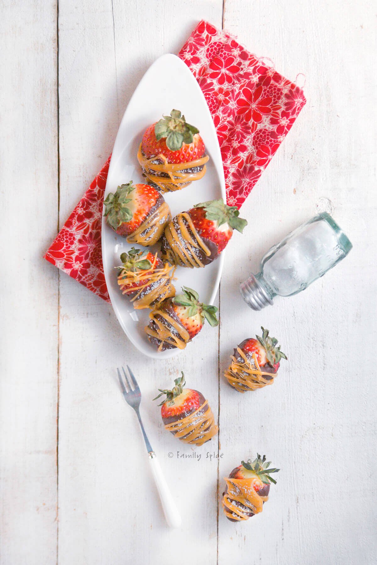 Top view of a white plate with chocolate and caramel covered strawberries.