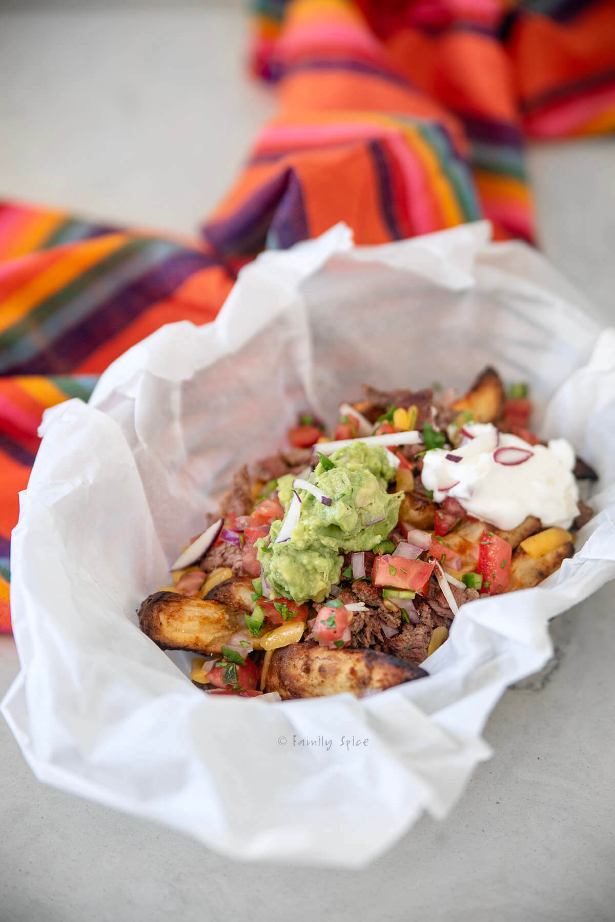 Fully loaded carne asada fries in a parchment lined basket.