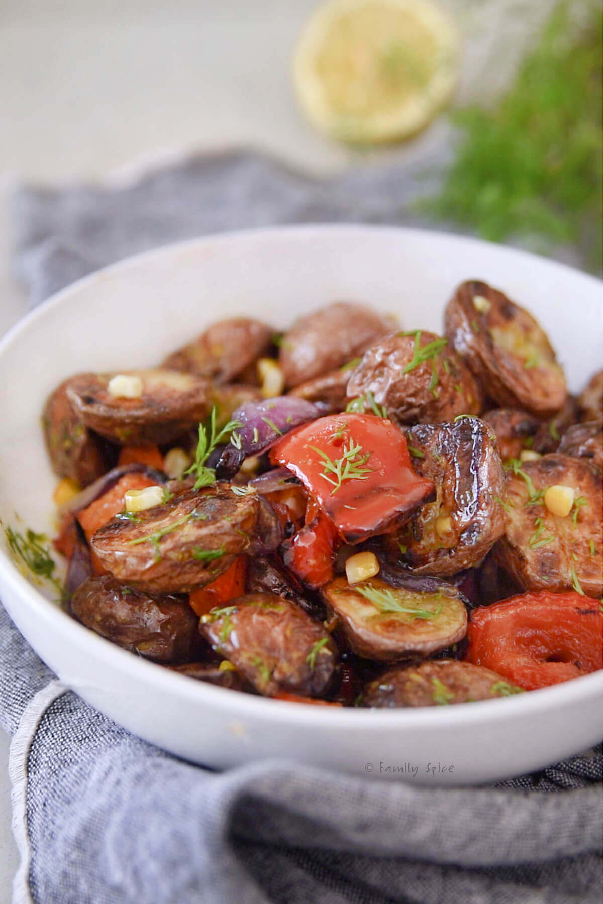 Grilled potato salad with mustard dressing in a white bowl.