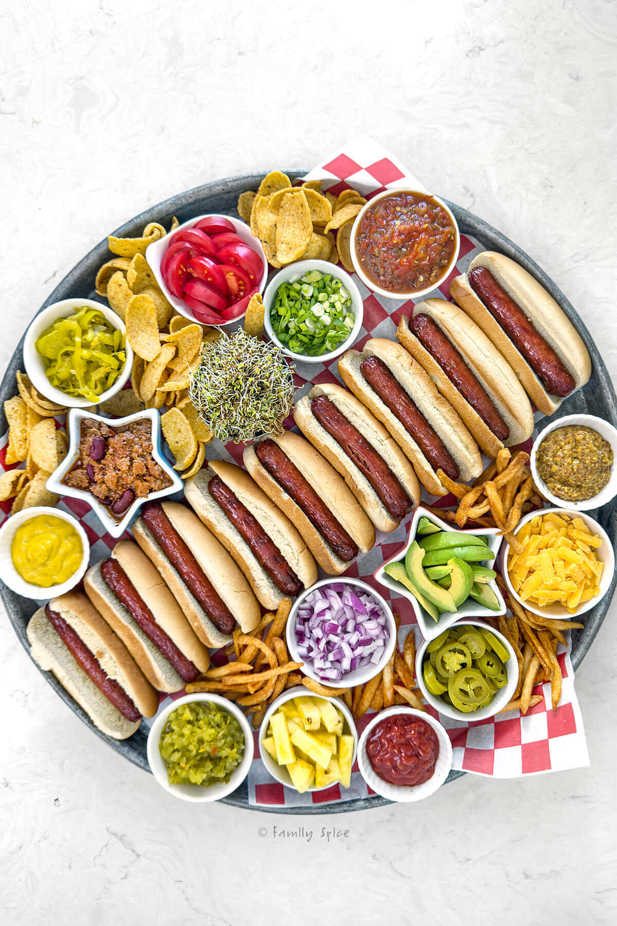 Top view of a tray showing hot dogs and lots of toppings for a hot dog board.