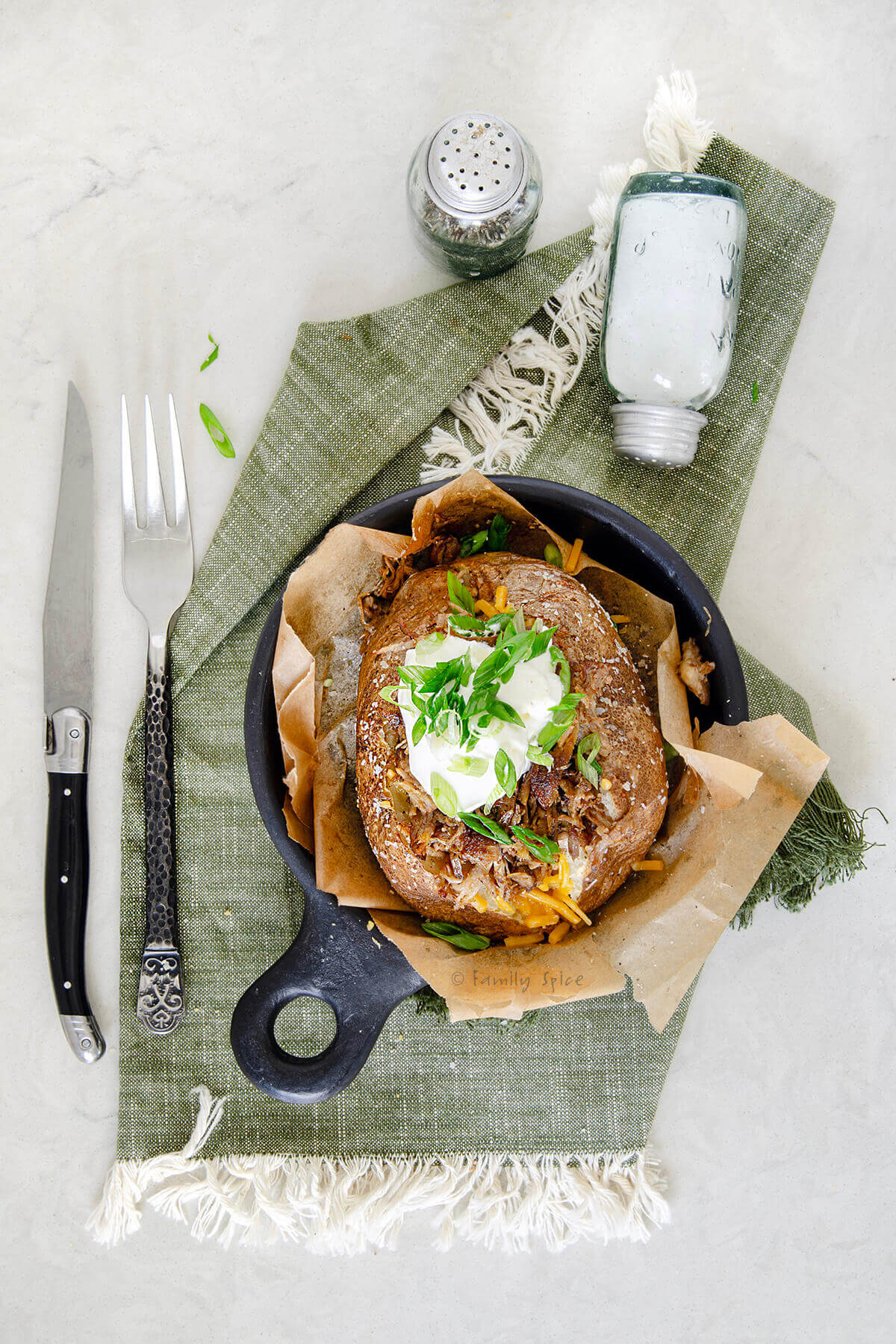 Top view of a fully loaded pulled pork baked potato.