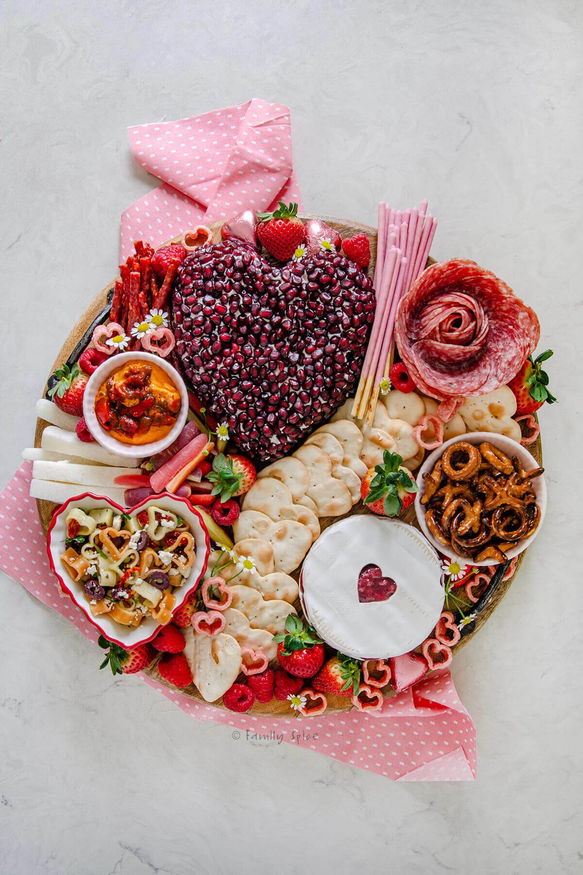 A valentine charcuterie board on a round wooden tray. 