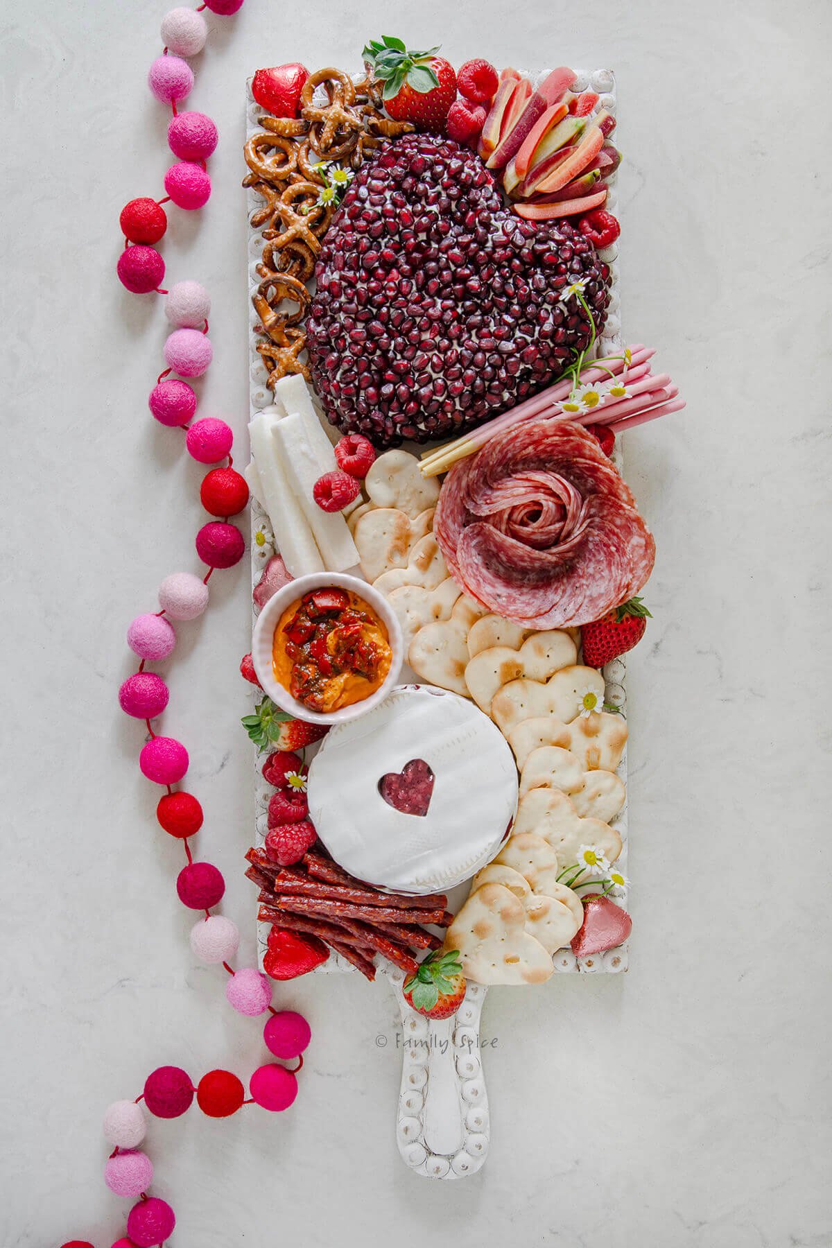 A valentine charcuterie board on a long white rectangle cutting board.