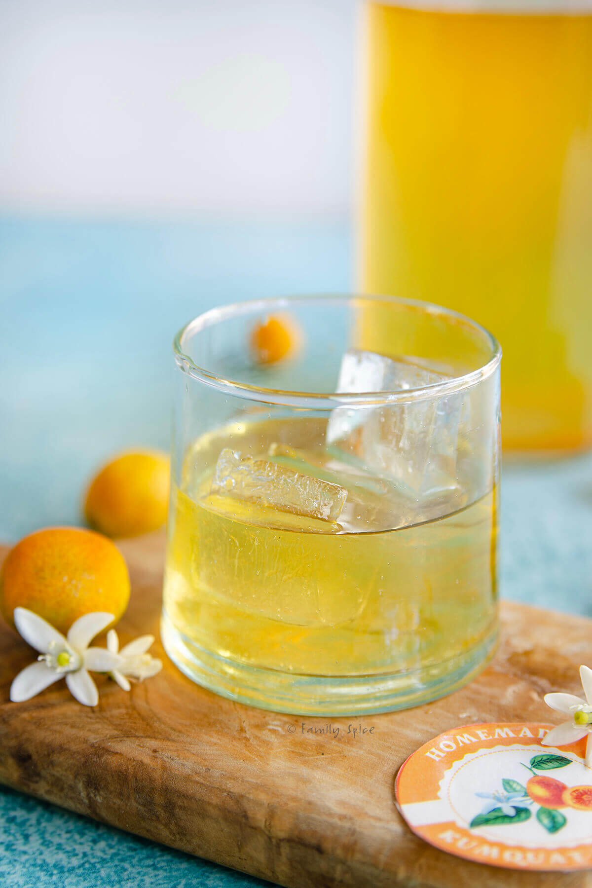 Closeup of a glass with kumquat liqueur with a bottle with more behind it.