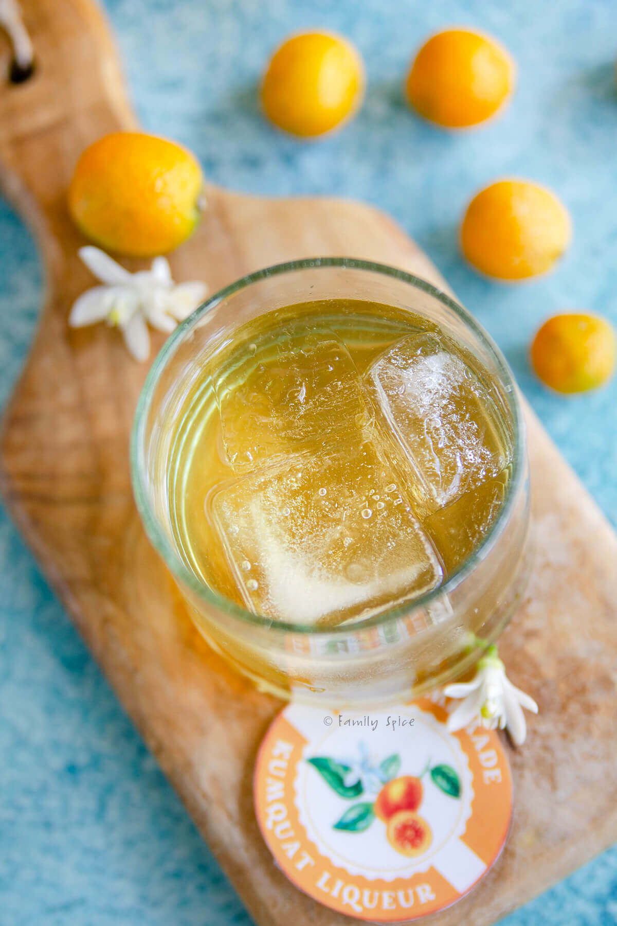 Top view of a glass with kumquat liqueur sitting on a small wooden cutting board.