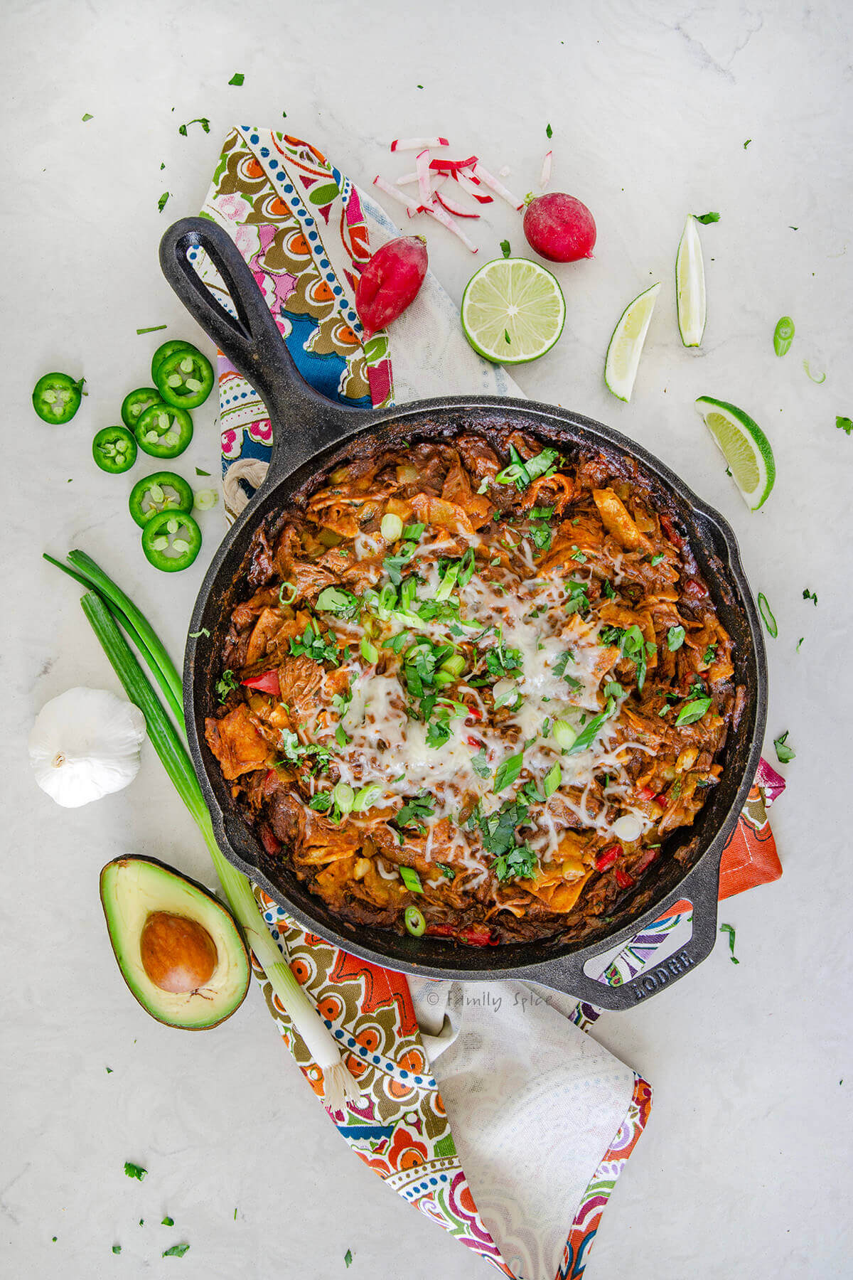 Top view of pulled pork enchilada skillet with various ingredients around it.