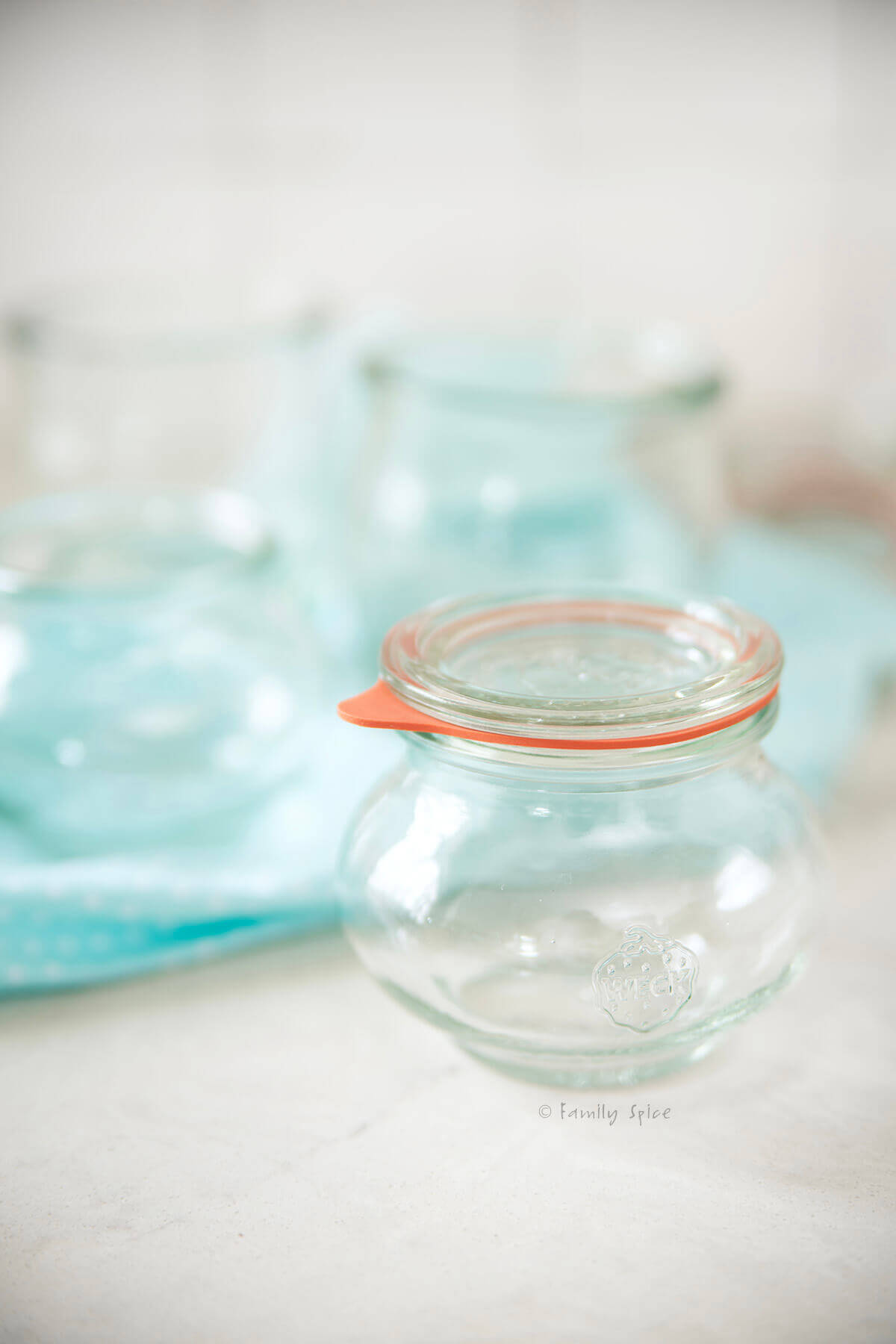 Closeup of an empty Weck glass jar and other jars behind it.