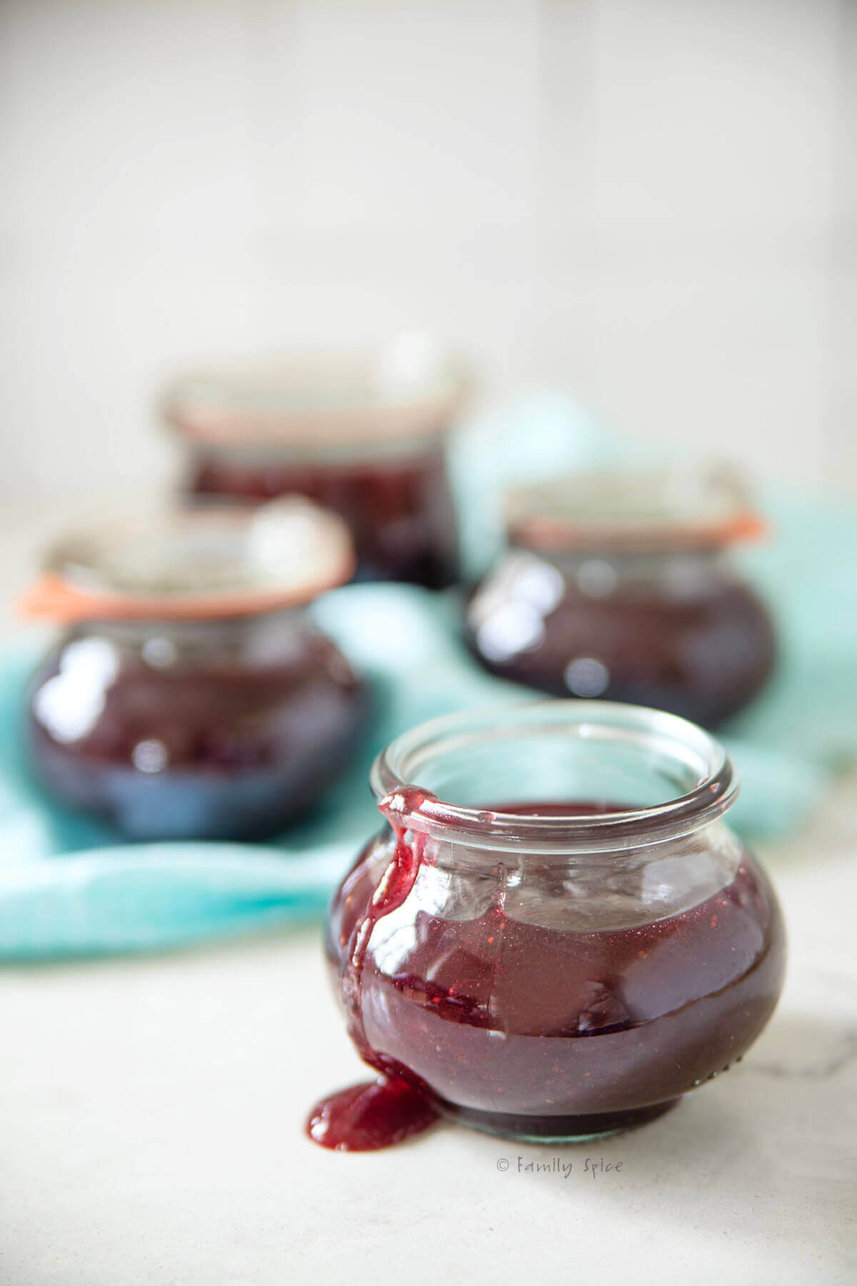 Closeup of a jar of mixed fruit jam with three more jars behind it.