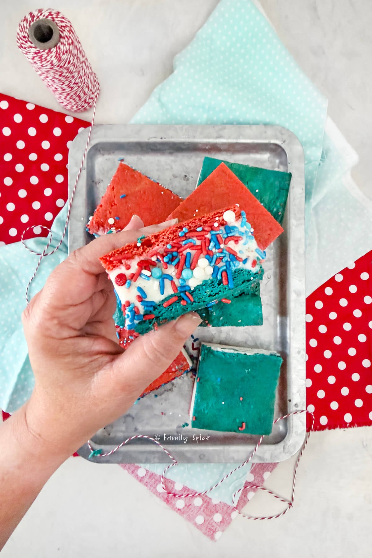Close up of a hand holding a red, white and blue ice cream sandwich with more underneath it.