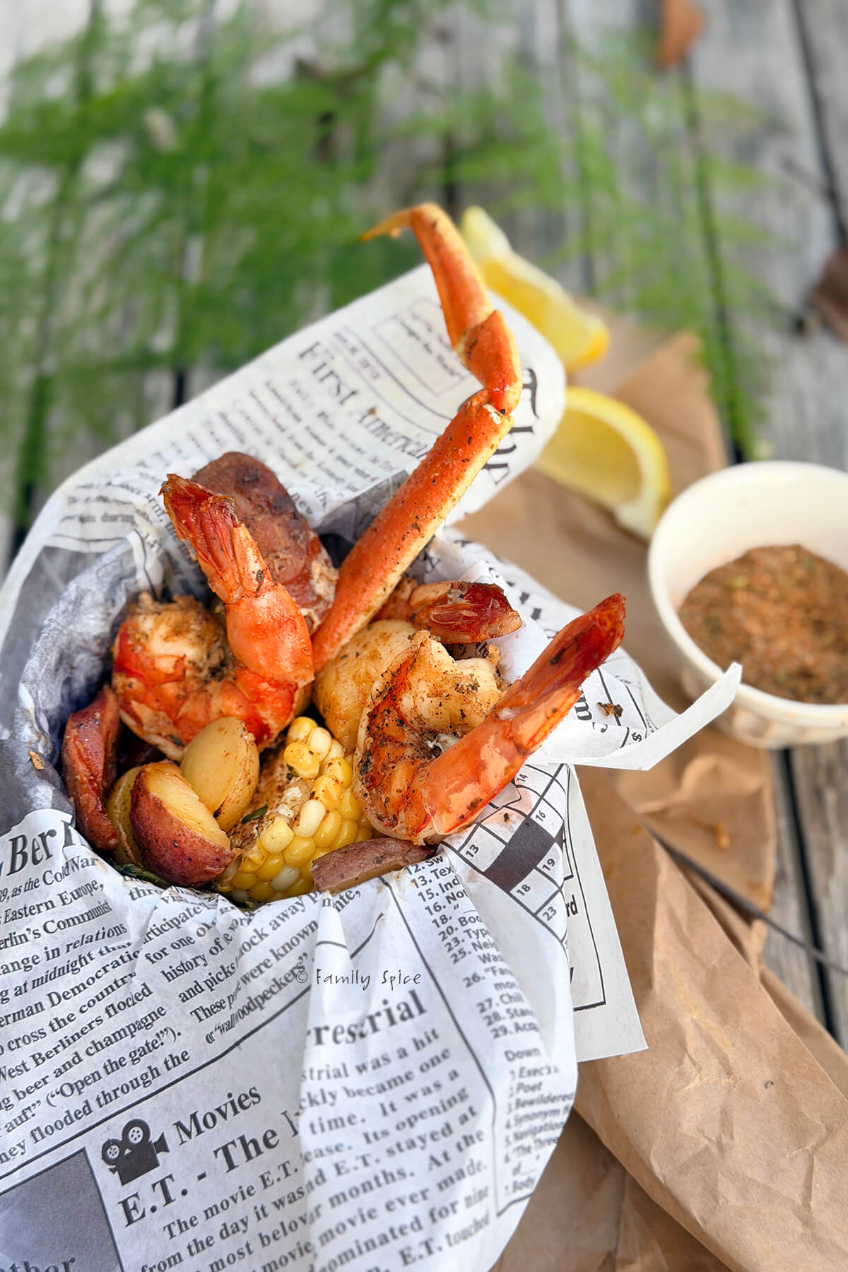 A campfire seafood dinner served up in a small metal bucket with newspaper parchment paper.