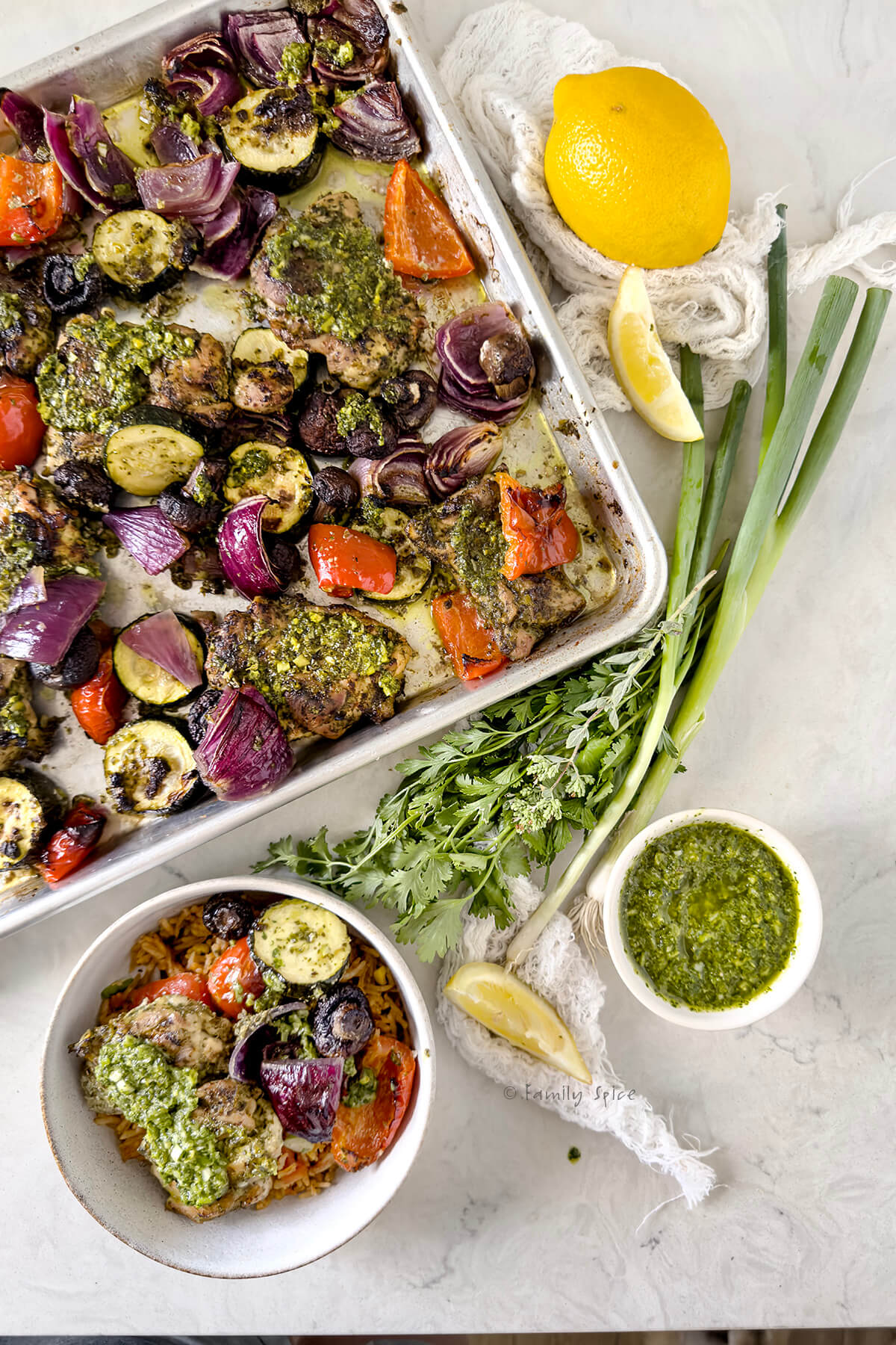 Top view of sheet pan chicken chimichurri with vegetables with a bowl holding a single serving next to it.