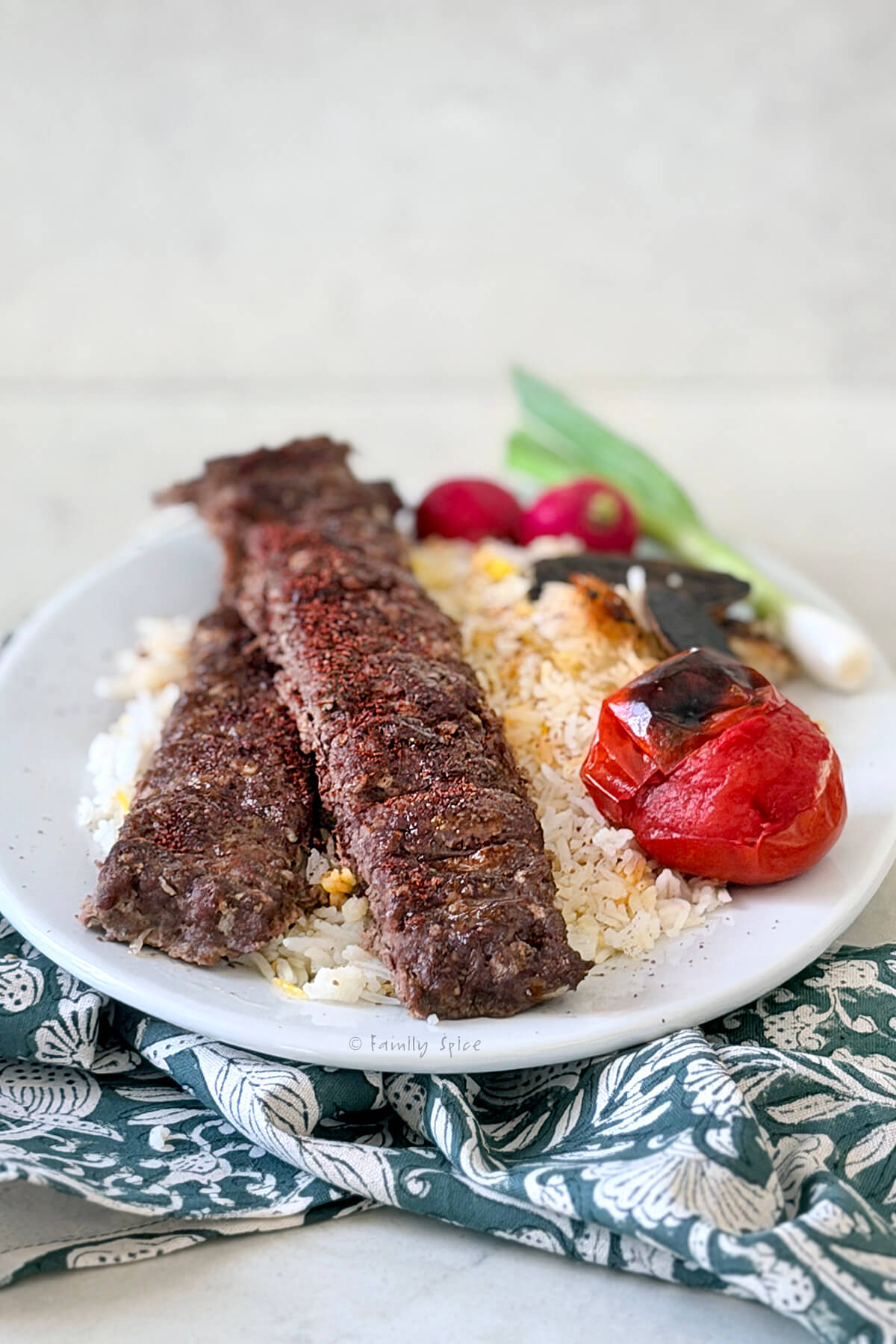 Side view of a plate with oven baked koobideh kabob on basmati rice.