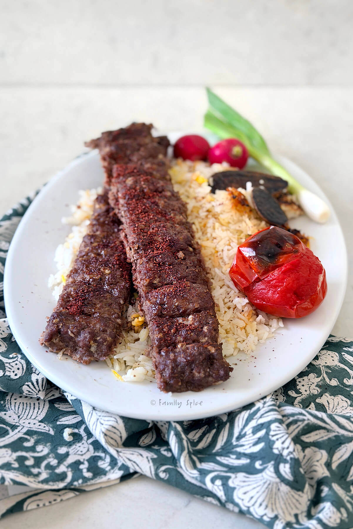 Closeup of a plate with oven baked koobideh kabob on basmati rice.