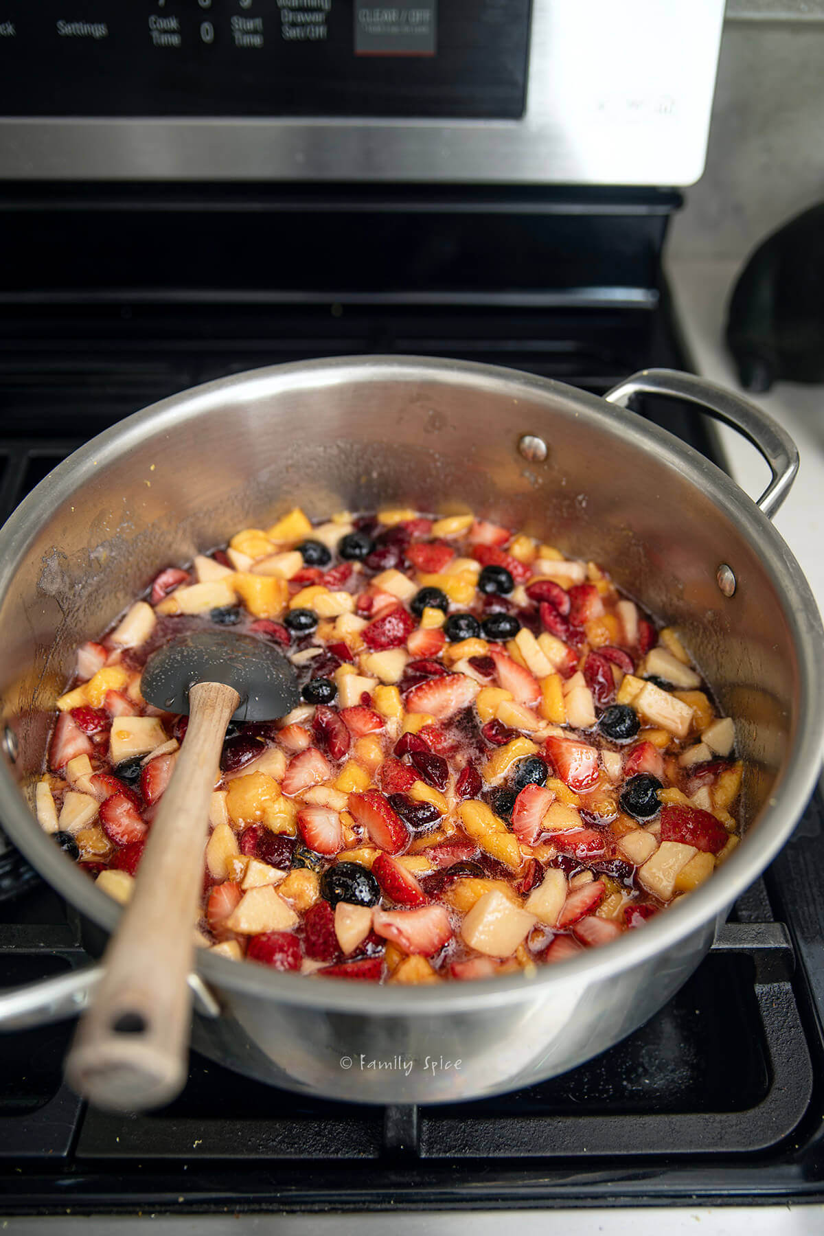 A pot with chopped fruits in it to make mixed fruit jam.