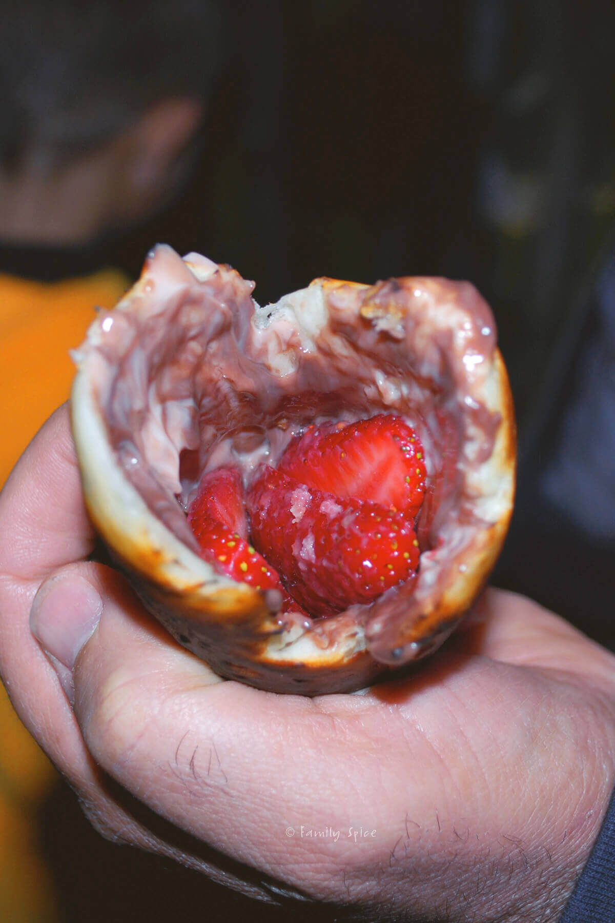 Strawberry slices inside a cooked campfire eclair with chocolate pudding inside