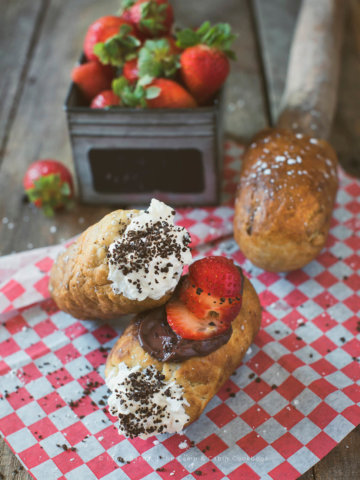 Campfire Eclairs stuffed with whipped cream, topped with chocolate pudding and strawberry slices