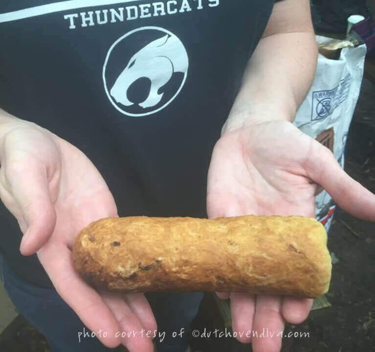 A pair of hands holding a baked campfire eclair dough