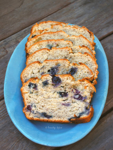 An oval blue plate with banana blueberry bread slices on it