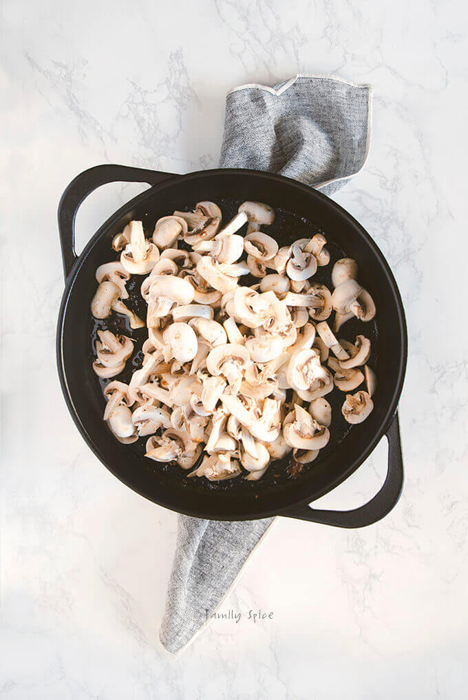 Sliced mushrooms in a large cast iron pan