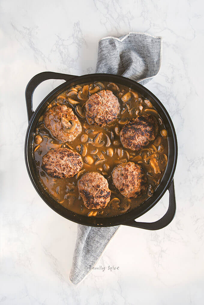 Salisbury steak with mushroom sauce cooked in a large cast iron pan
