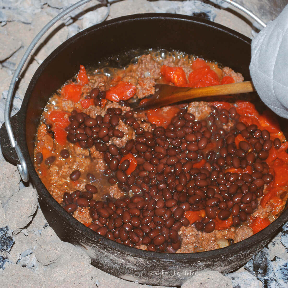 Adding black beans to chili mixture in cast iron dutch oven