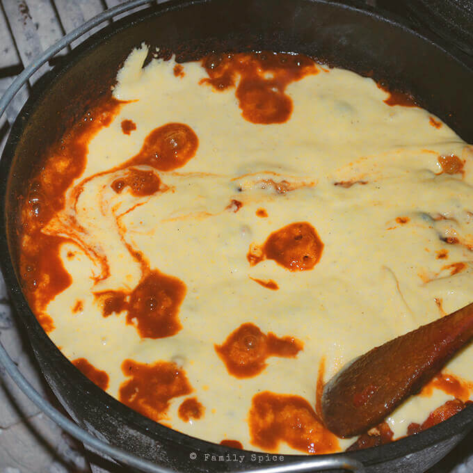 Adding the cornbread batter on top of the chili to make Dutch Oven Chili with Cornbread by FamilySpice.com