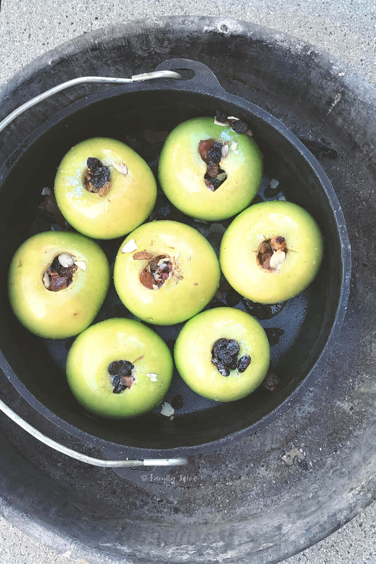 Top view of a cast iron Dutch oven with stuffed baked apples in it