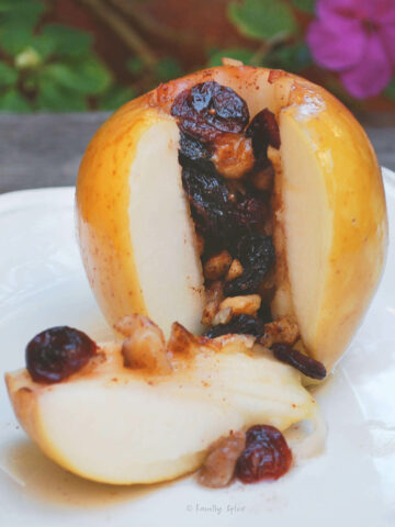 A baked apple stuffed with nuts and raisins with a wedge cut out