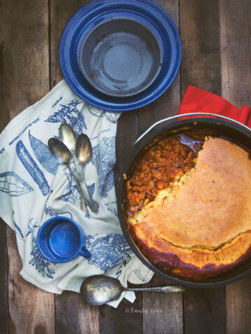 Top view of a cast iron dutch oven with chili and cornbread in it