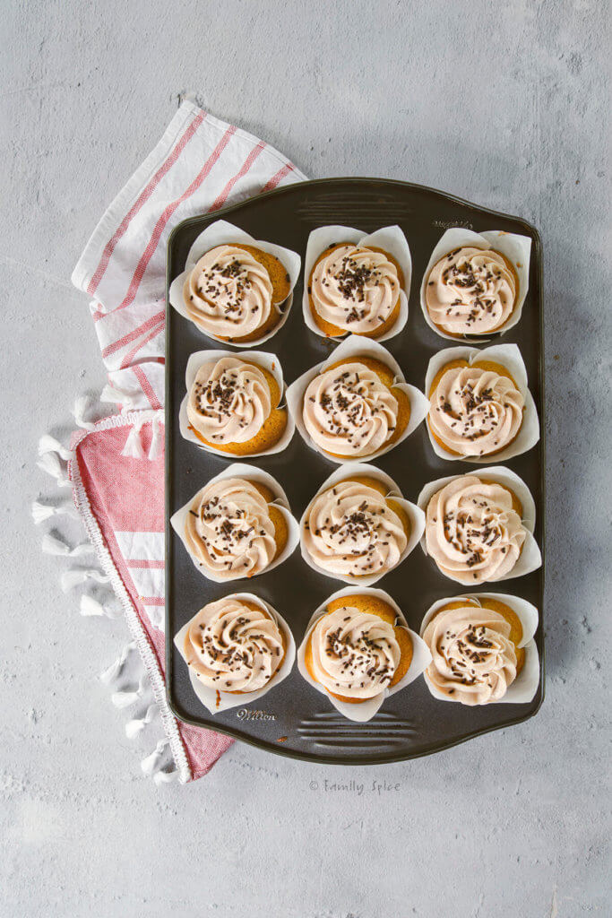 A 12-count cupcake tray with frosted Baileys cupcakes garnished with chocolate jimmies