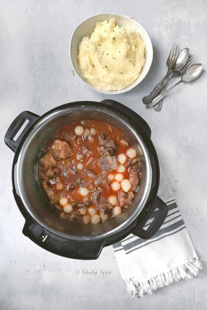 The final beef bourguignon cooked in the instant with a bowl of mashed potatoes next to it