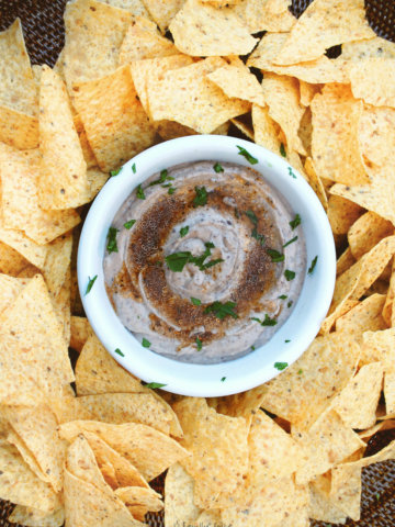 Top view of a basket with tortilla chips and black bean hummus