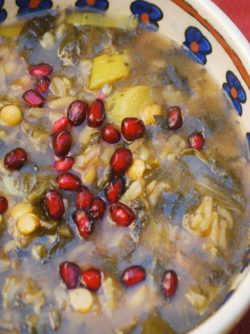 Closeup of a bowl of ash anar (persian pomegranate soup) topped with pomegranate arils