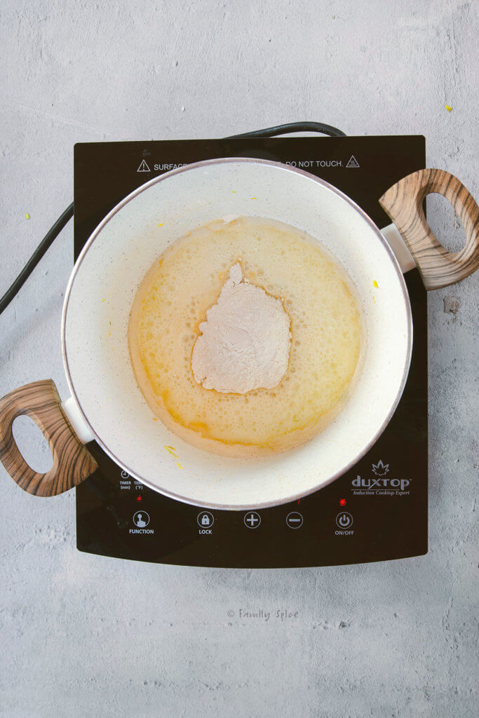 A pot on a cooktop with melted butter and flour in it