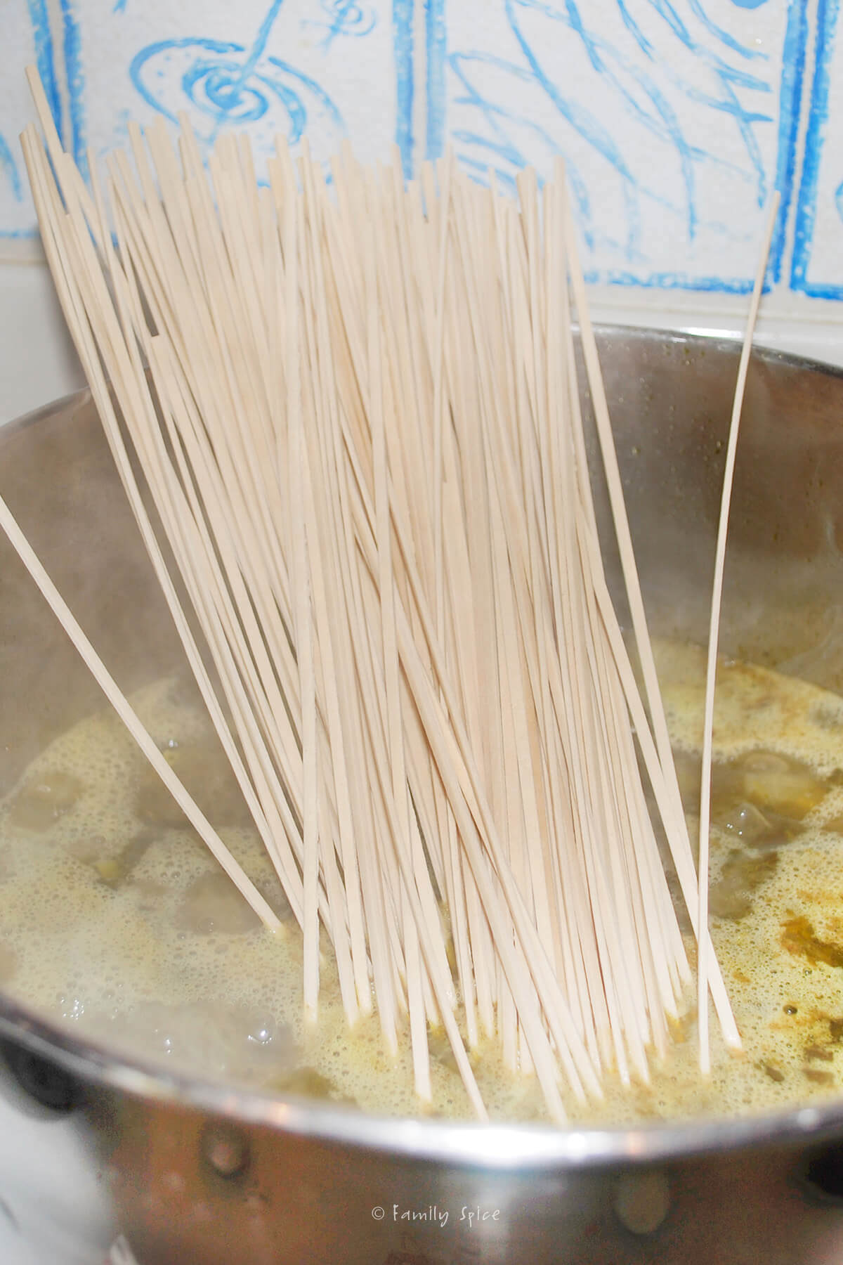 Adding reshteh noodles into a pot of ash reshteh