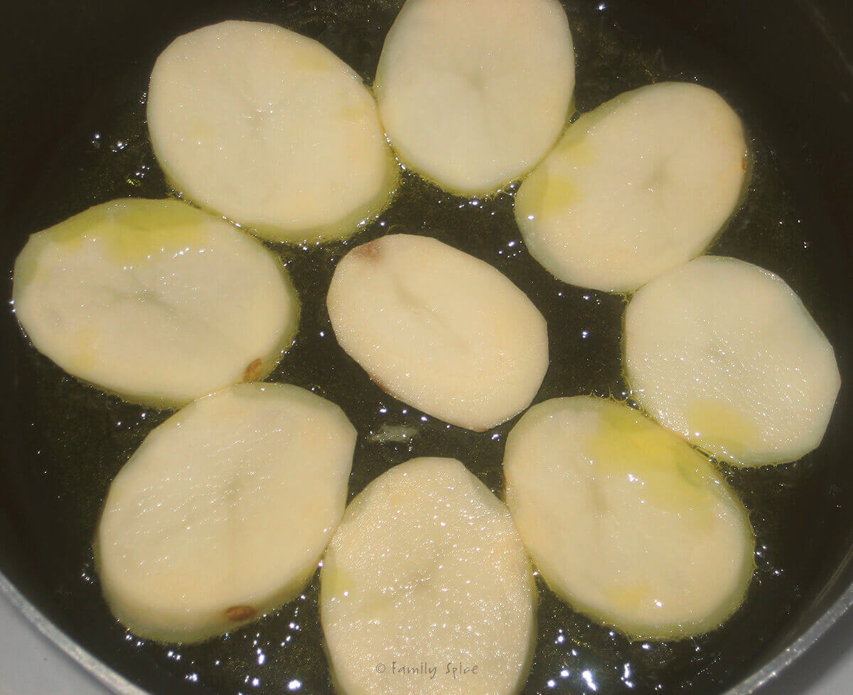 Potato slices frying in oil in a nonstick pot