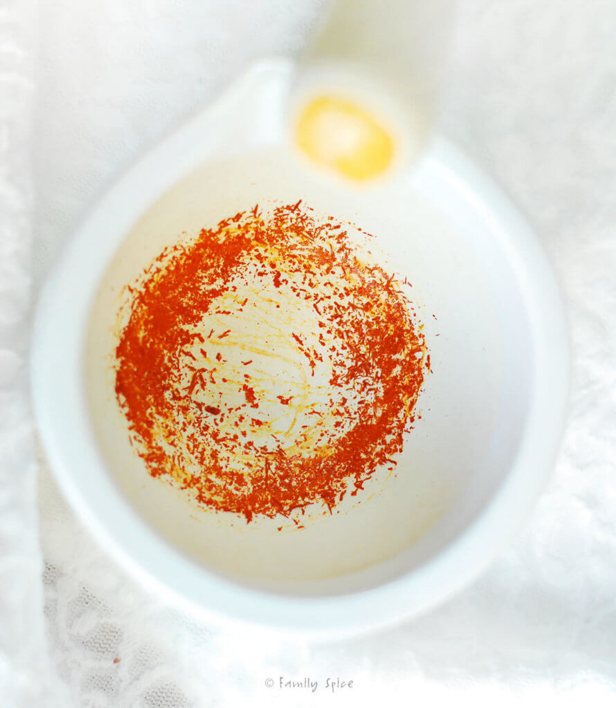 Crushed saffron in a white mortar with a pestle next to it