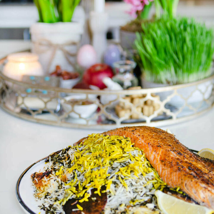 Side view of a round platter with sabzi polo ba mahi (persian herb rice with salmon)