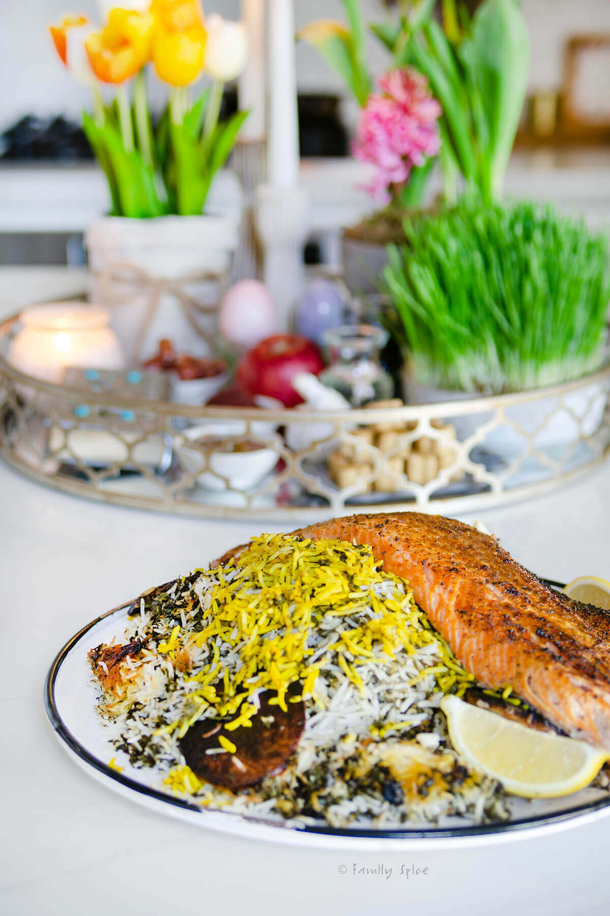 Side view of a round platter with sabzi polo ba mahi (persian herb rice with salmon)