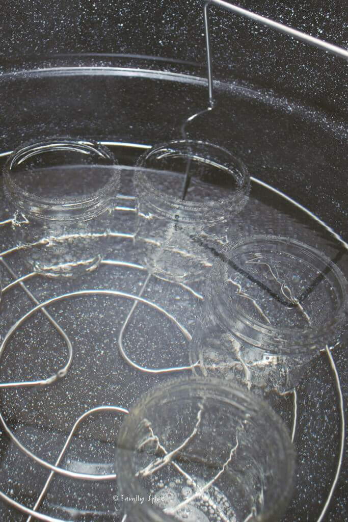 Glass mason jars in a large pot with hot water in order to sterilize them