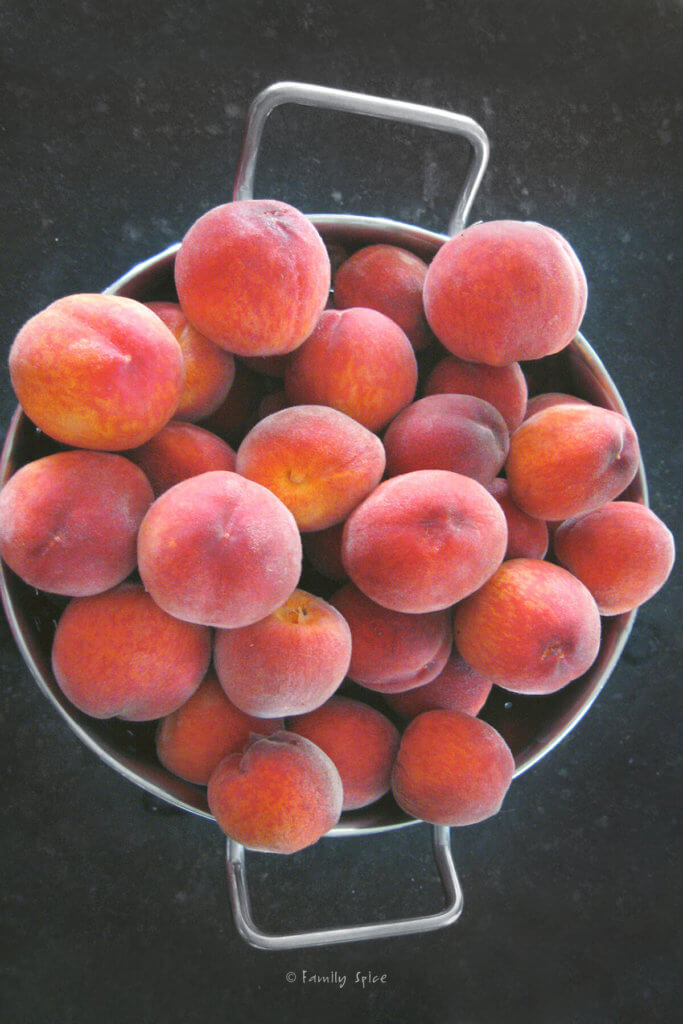 A whole lot of peaches in a large metal colander