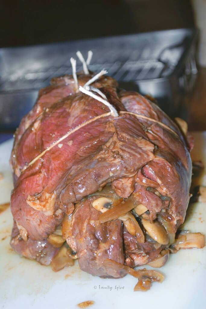 A butterflied leg of lamb stuffed with mushrooms and herbs, tied with twine and ready to roast