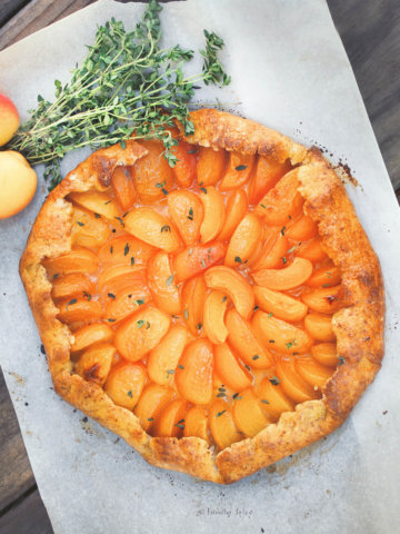 Overhead view of a freshly baked apricot galette with sprigs of fresh thyme next to it