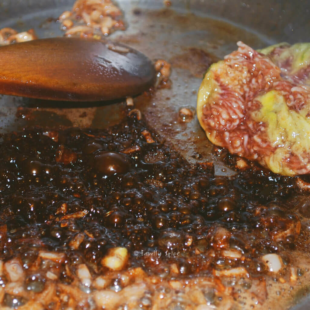 Adding balsamic vinegar and fig to browned onions in a stainless pan