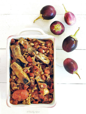Khoresh bademjan (persian eggplant stew) in a white dish with baby eggplant next to it