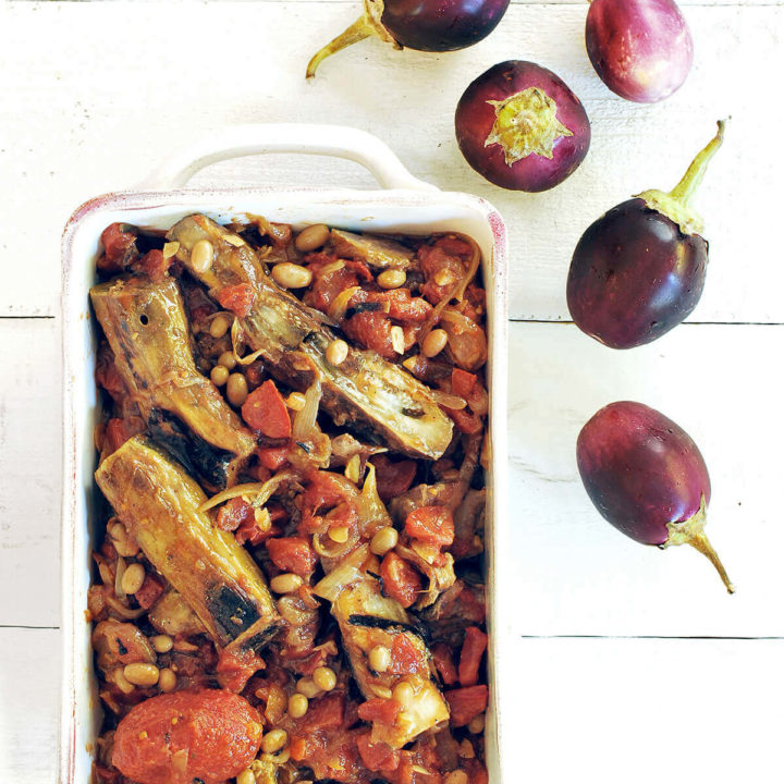 Khoresh bademjan (persian eggplant stew) in a white dish with baby eggplant next to it