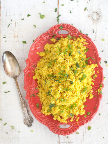 Golden yellow turmeric cauliflower rice on a red platter